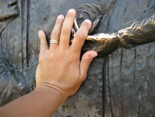 Medjugorje mano che tocca le mani della Madonna su icona. Pellegrinaggio in aereo Tu Sei Pietro Viaggi