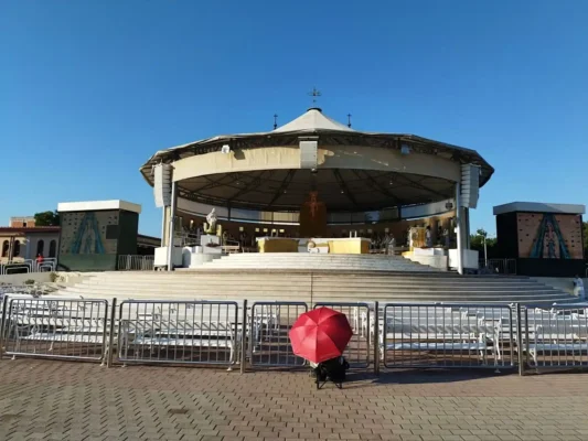 Medjugorje pagoda celebrazioni esterno. Chiesa San Giacomo con persone che si ripara dal sole con un ombrello. Pellegrinaggio a Medjugorje Tu Sei Pietro Viaggi
