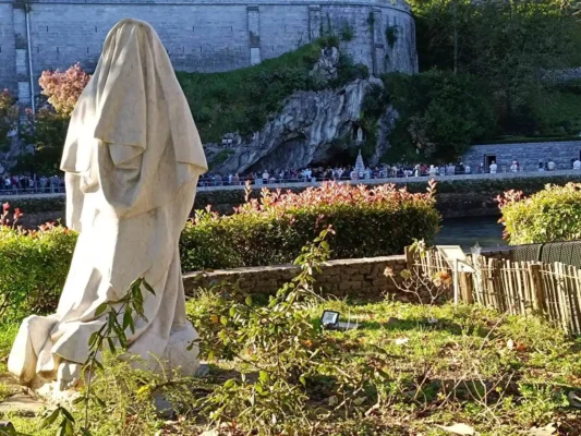 Lourdes, statua Santa Bernadette che guarda la grotta delle apparizioni. Pellegrinaggio a Lourdes Tu sei Pietro Viaggi.