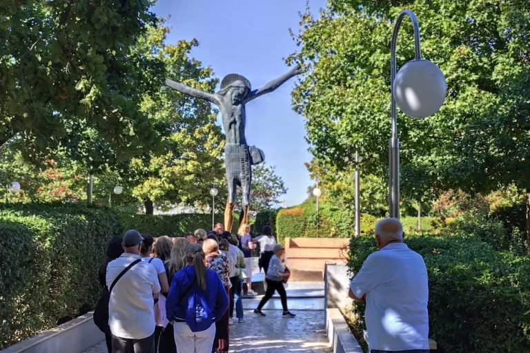 Gruppo di pellegrini davanti alla statua del Cristo Risorto tra gli alberi a Medjugorje